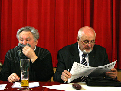 Gustav Knauber hält sich den Mund zu, Klaus Weirich liest in der Dokumentation